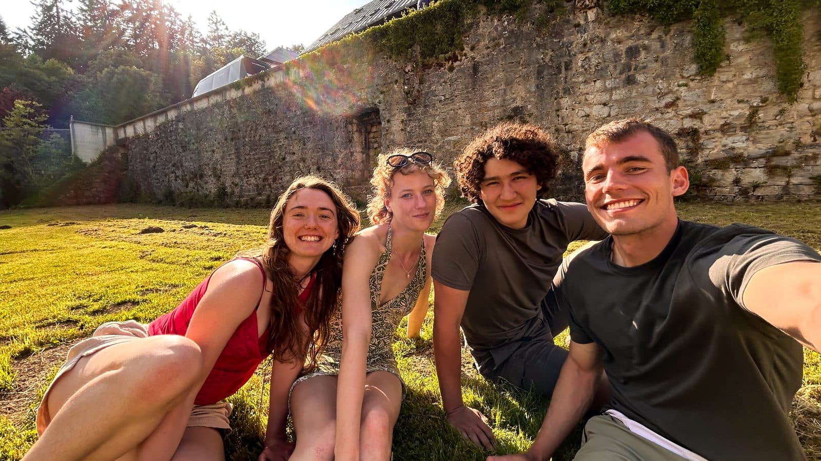 Kyle and three fellow pilgrims resting on the grass beside an old stone wall in the first days of the walk.