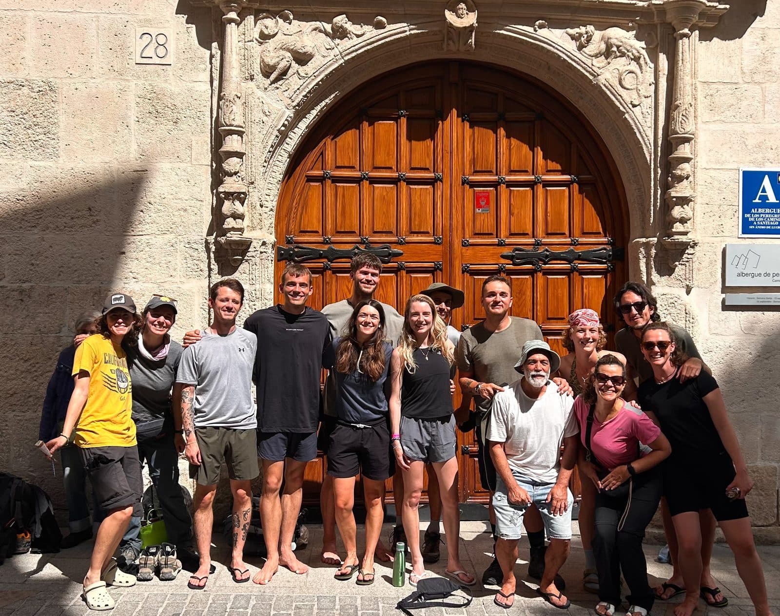 Pilgrim friends gathered at night before a carved Baroque church doorway.
