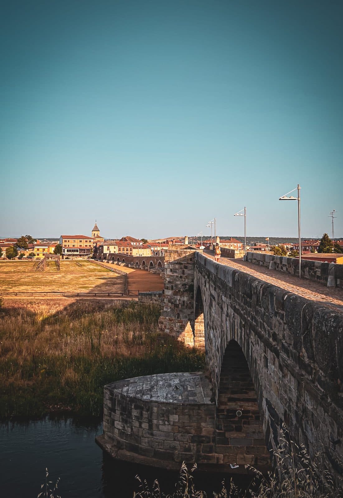 A long medieval stone bridge spanning the river into a small town west of León.