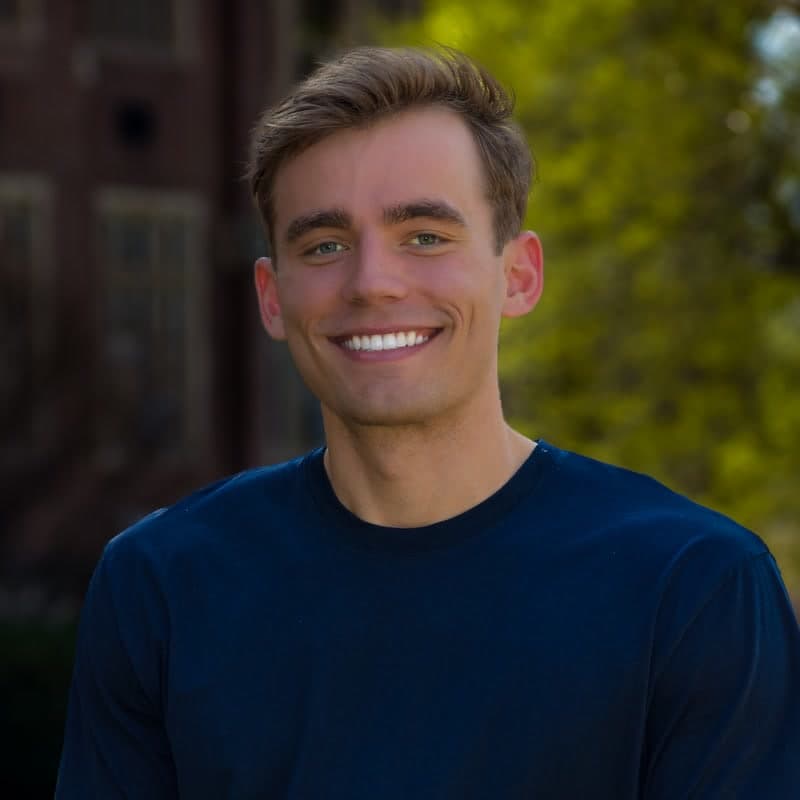 Kyle Wisniewski, head and shoulders, outdoors on a university campus in a navy crew-neck shirt