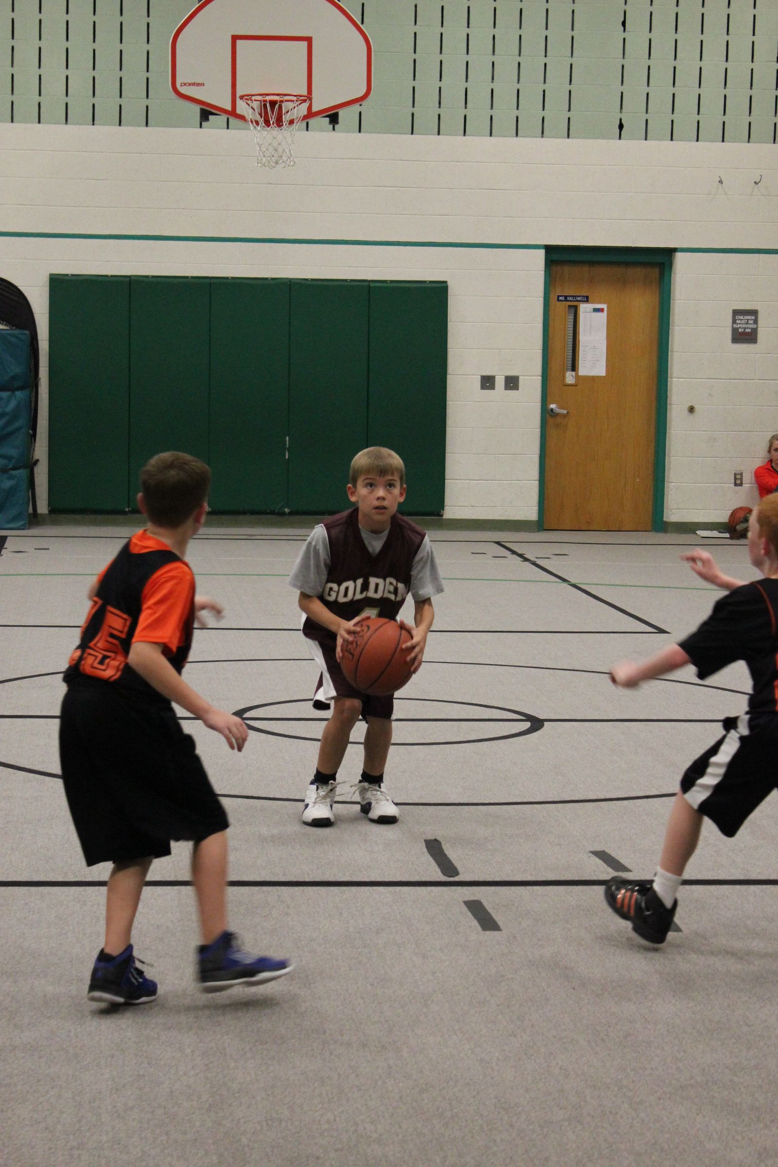 A young Kyle Wisniewski in a grey Golden jersey holding a basketball on an indoor court, other young players around him.