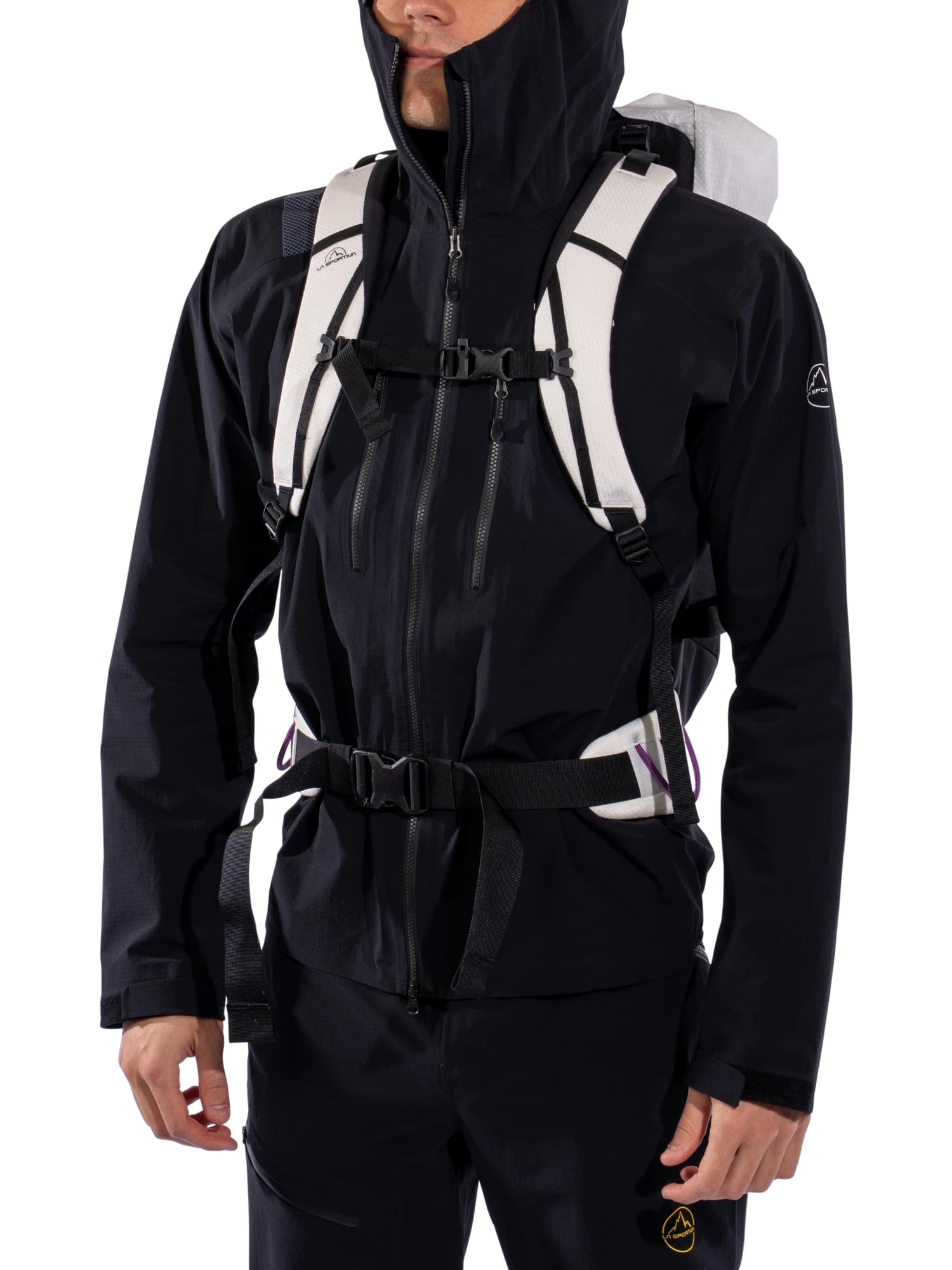 Kyle Wisniewski, hood up, in a black La Sportiva shell jacket with a white backpack buckled at chest and waist, on white