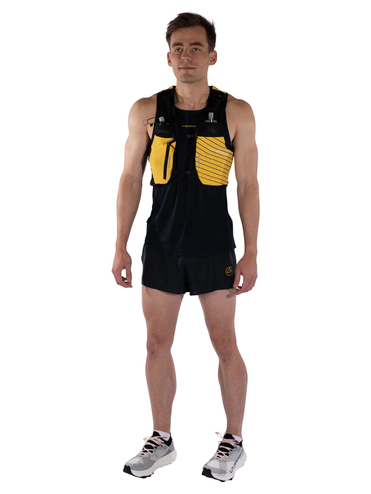 Kyle Wisniewski, full length, in a black and yellow La Sportiva running vest, black shorts and white running shoes, on white